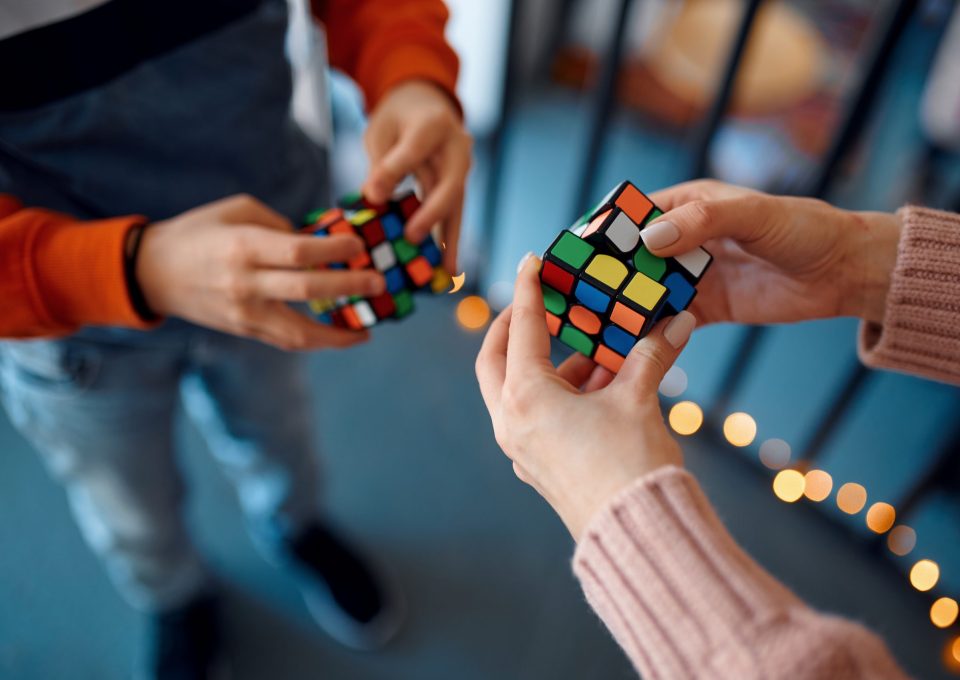 People play with puzzle cubes, intellectual rest. Toy for brain and logical mind training, creative game, solving of complex problems